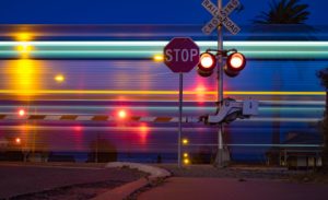 The picture shows a railroad crossing with a train speeding through.