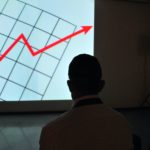 The photo shows a man looking at a graph projected on a screen.