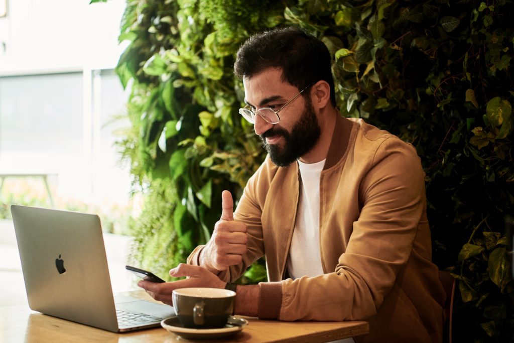 The picture shows a man looking at his computer and giving the thumbs up because he saved on his taxes. 