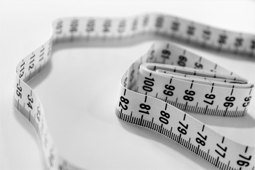 The picture shows a measuring tape to symbolize minimizing Medicare premium surcharges.