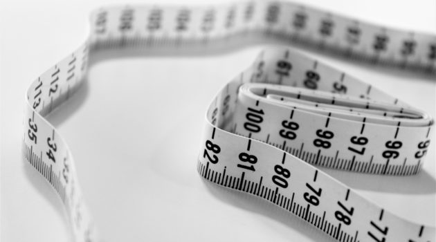 The picture shows a measuring tape to symbolize minimizing Medicare premium surcharges.