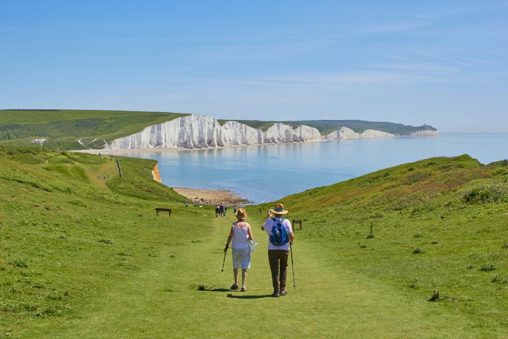 The picture shows an older couple hiking on a beautiful day to represent retirement and the SECURE Act.