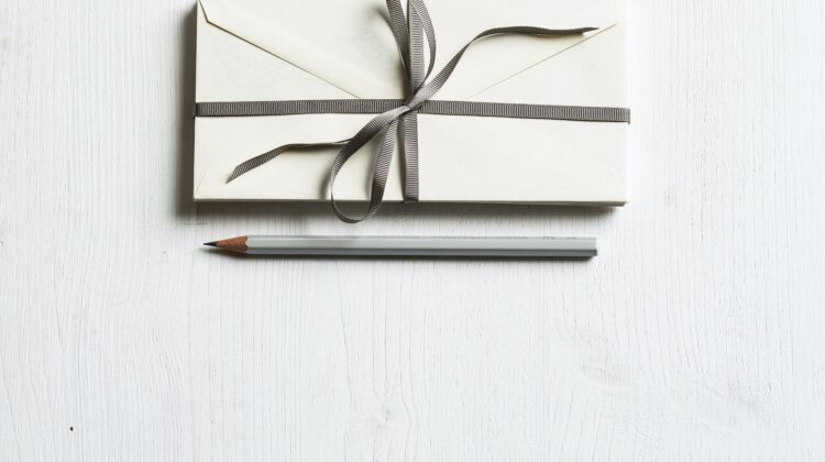 The picture is of envelopes and a pencil to represent charitable giving and, in particular, qualified charitable donations (QCDs).