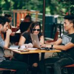 The picture shows 3 young adults seated at a table to represent financial accounts for young adults.