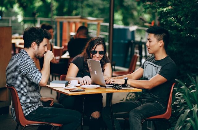 The picture shows 3 young adults seated at a table to represent financial accounts for young adults.