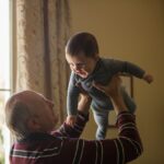 The picture is of a grandfather playing with his baby grandchild to represent the Social Security Family Benefit.