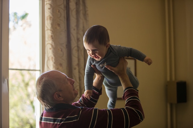 The picture is of a grandfather playing with his baby grandchild to represent the Social Security Family Benefit.