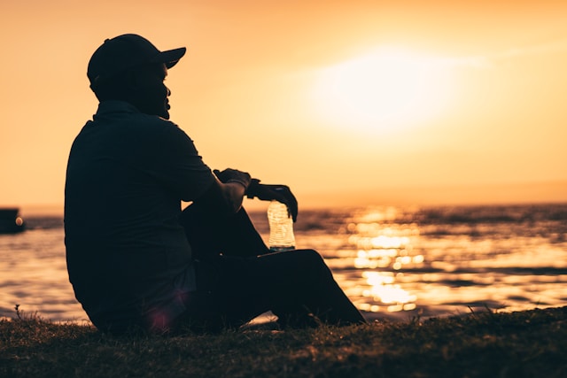The picture is of an older man sitting alone at the beach at sunset to represent survivor benefits from Social Security.